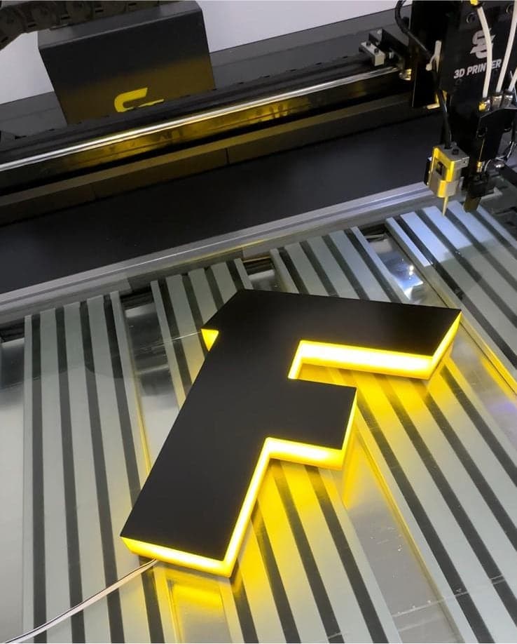 A letter F with a black face and a halo glow, on the printer bed